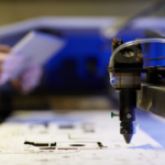 man holds a notebook on a blurred background and cnc machine