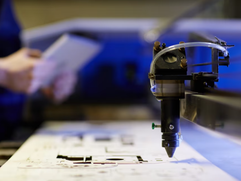 man holds a notebook on a blurred background and cnc machine