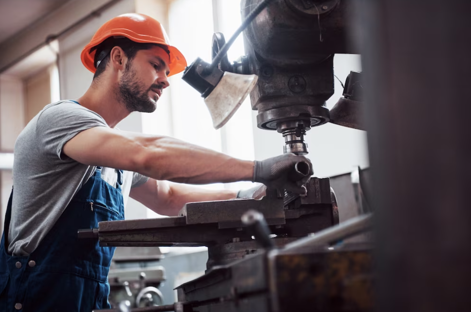 man in suit and helmet working on cnc machine