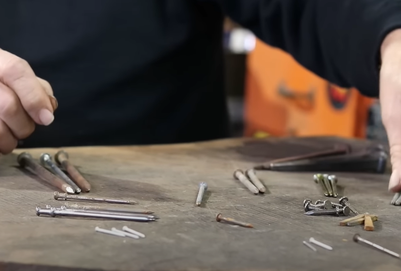 Person seated in front of a table with lots nails and hardware