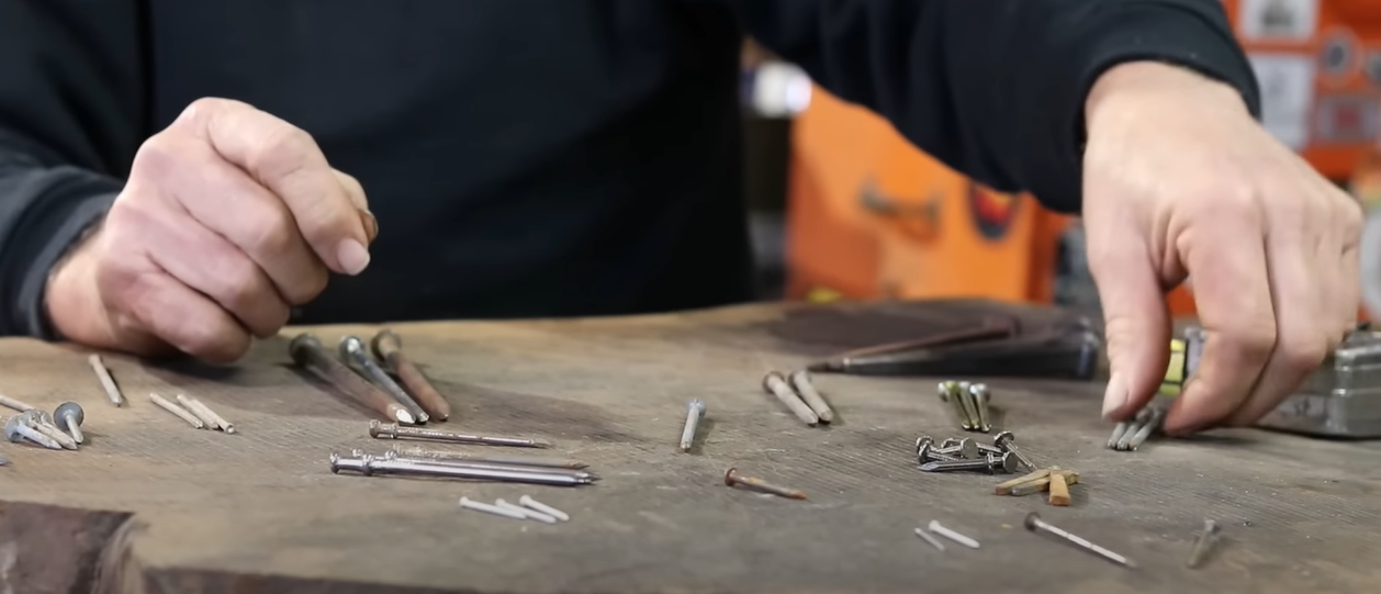 Person seated in front of a table with lots nails and hardware