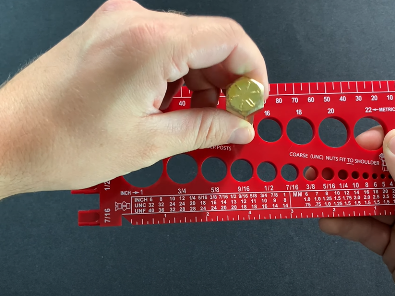 Hand measuring a nail with a chart