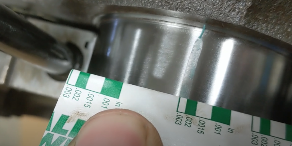 Hand holding plastic gauge with a machine beneath