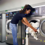 a woman takes the laundry out of an industrial washing machine