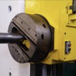 A close-up of a yellow and white industrial boring machine with a large chuck and a protruding cylindrical component