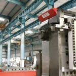 A wide-angle view of a large industrial hall featuring a floor type boring machine with a red and white upper housing